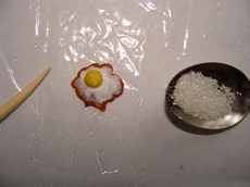 Зубочисткой придаем краям яичницы извилистую форму и берем щепотку сахара